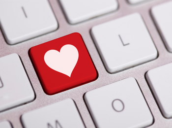A set of keys on a silver keyboard, one key is red with a white heart.